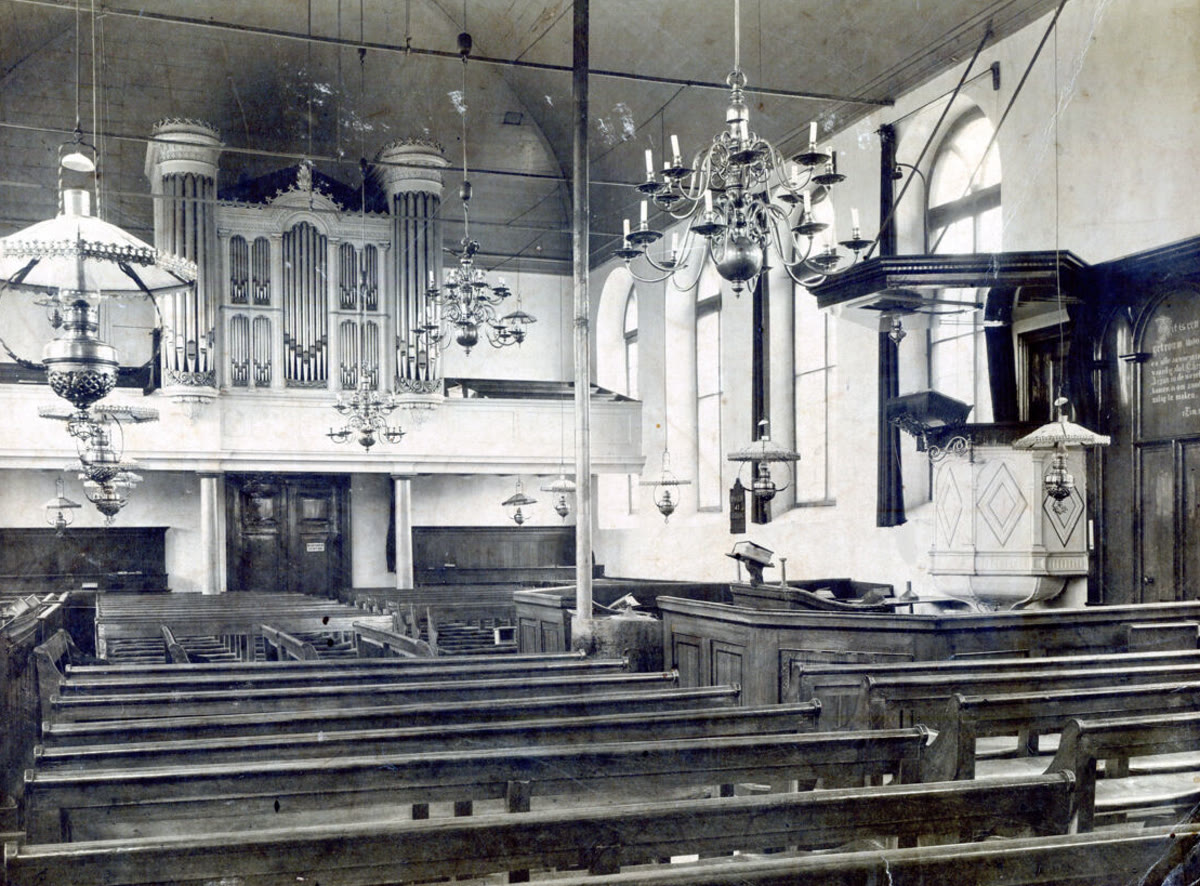Historisch interieur van de Dorpskerk met orgel, kaarsenkronen en banken