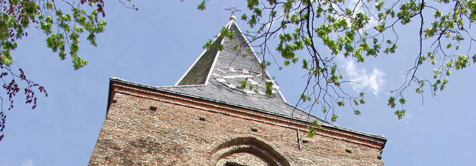 De bakstenen toren van de Dorpskerk met leien spits